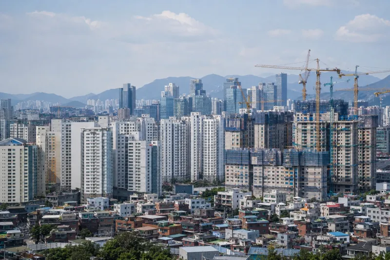 Urban Skyline with Cranes and Mountains